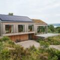 Moderne bæredygtig bolig med solceller og naturlige materialer på facaden